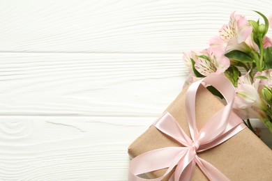 Photo of Happy Mother's Day. Beautiful flowers and gift box on white wooden table, flat lay. Space for text