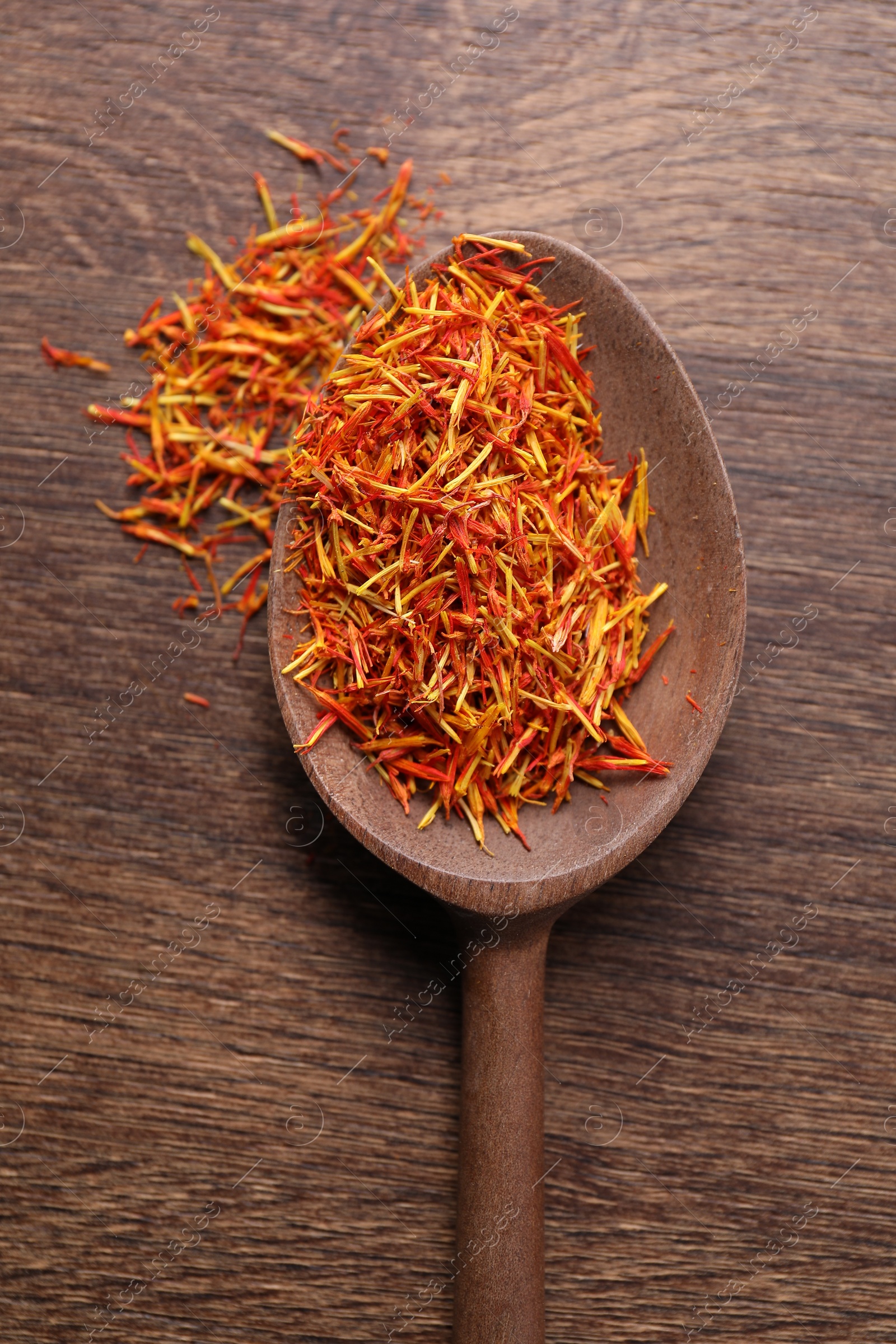 Photo of Aromatic saffron and spoon on wooden table, top view