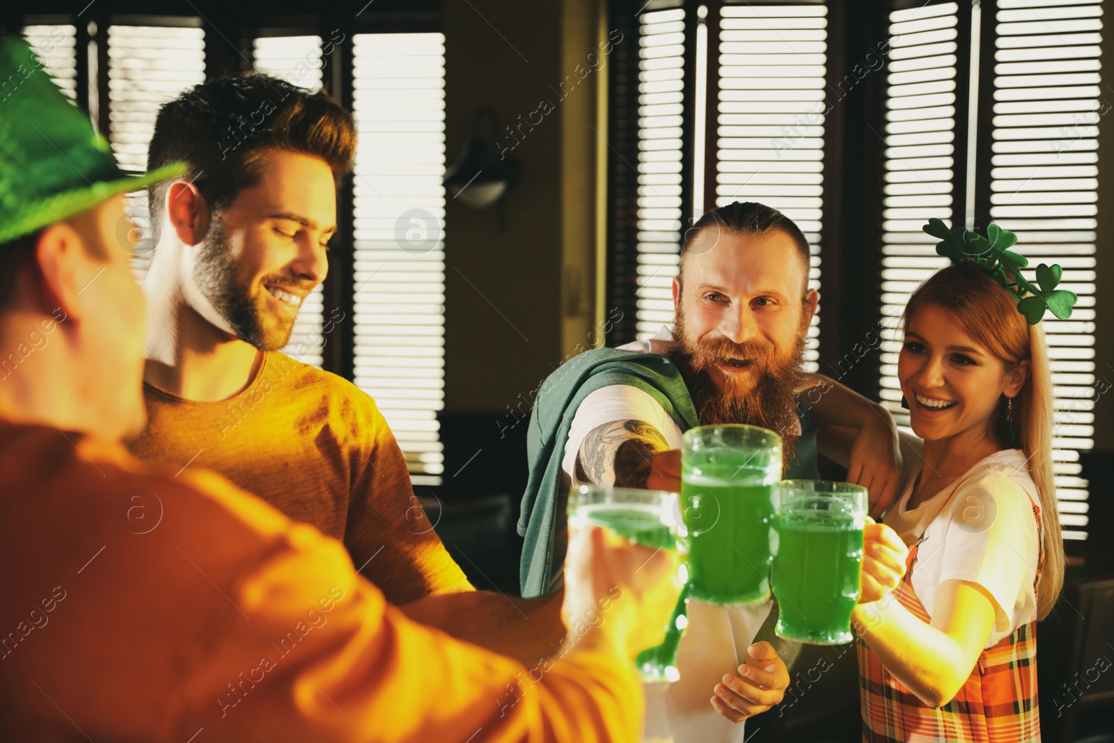 Photo of Group of friends toasting with green beer in pub. St. Patrick's Day celebration