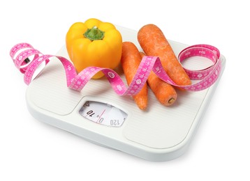 Photo of Scales, vegetables and measuring tape on white background