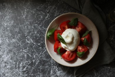 Photo of Delicious burrata cheese with tomatoes and basil on grey table, top view. Space for text