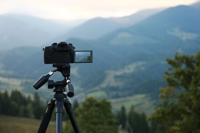 Photo of Taking video with modern camera on tripod in mountains