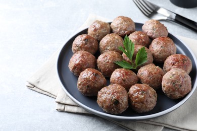 Photo of Tasty cooked meatballs with parsley served on light grey table