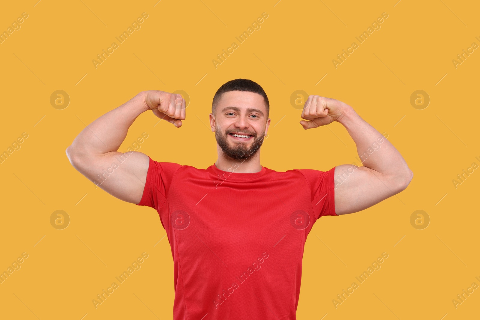 Photo of Portrait of handsome man showing muscles on yellow background