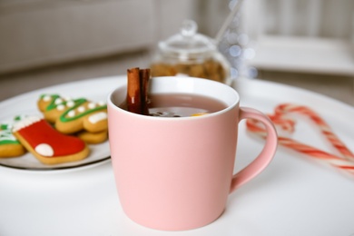 Photo of Cup of hot mulled wine on white table indoors. Winter drink