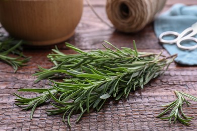 Photo of Sprigs of fresh rosemary on wooden table, closeup