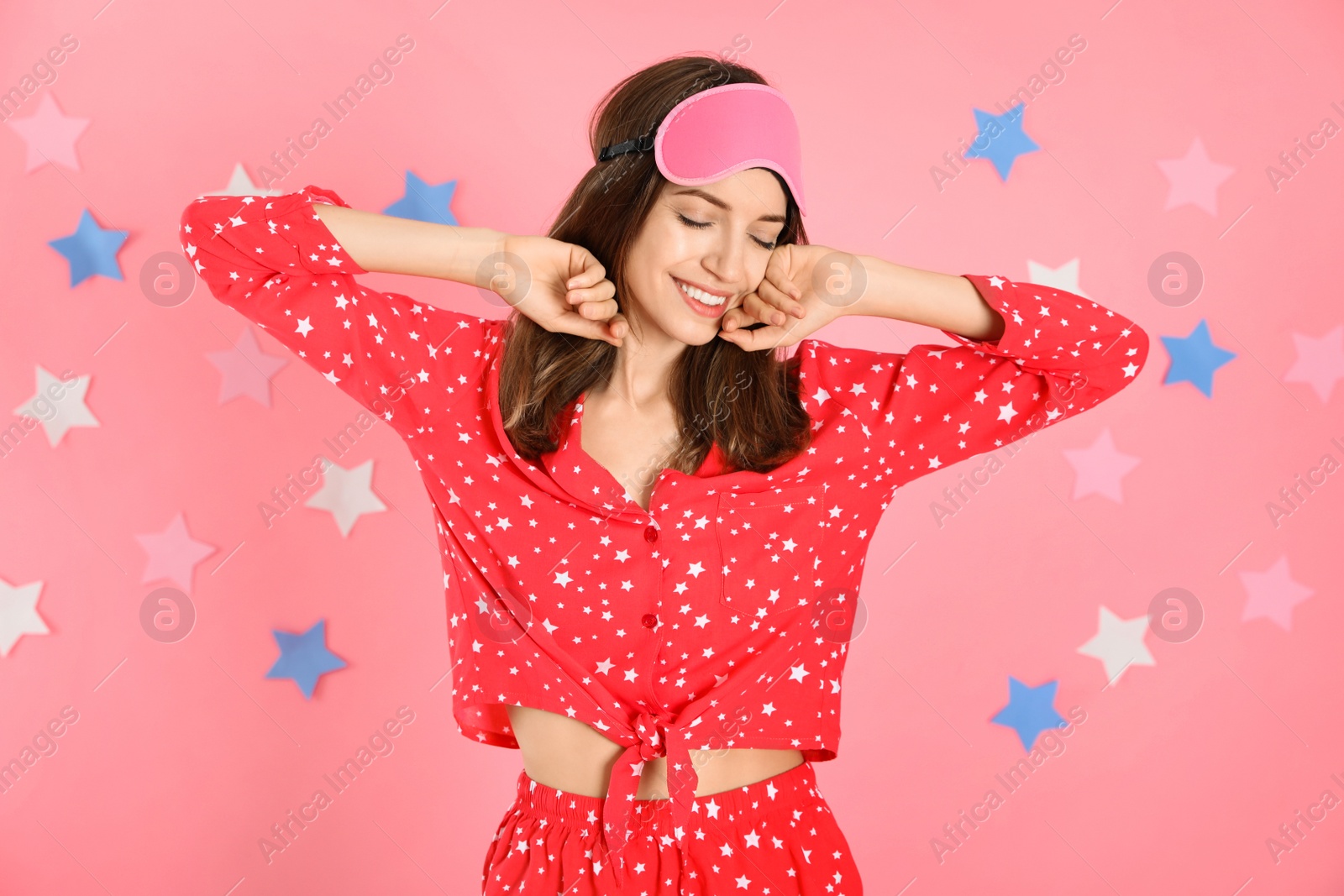 Photo of Beautiful woman wearing pajamas and sleep mask on pink background. Bedtime