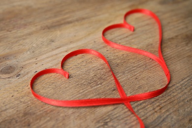 Photo of Hearts made of red ribbon on wooden background. Valentine's day celebration