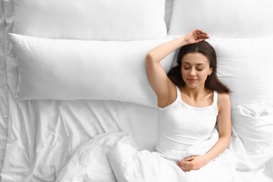 Portrait of beautiful young woman sleeping in large bed, above view