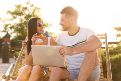 Image of Happy couple with laptop resting together outdoors