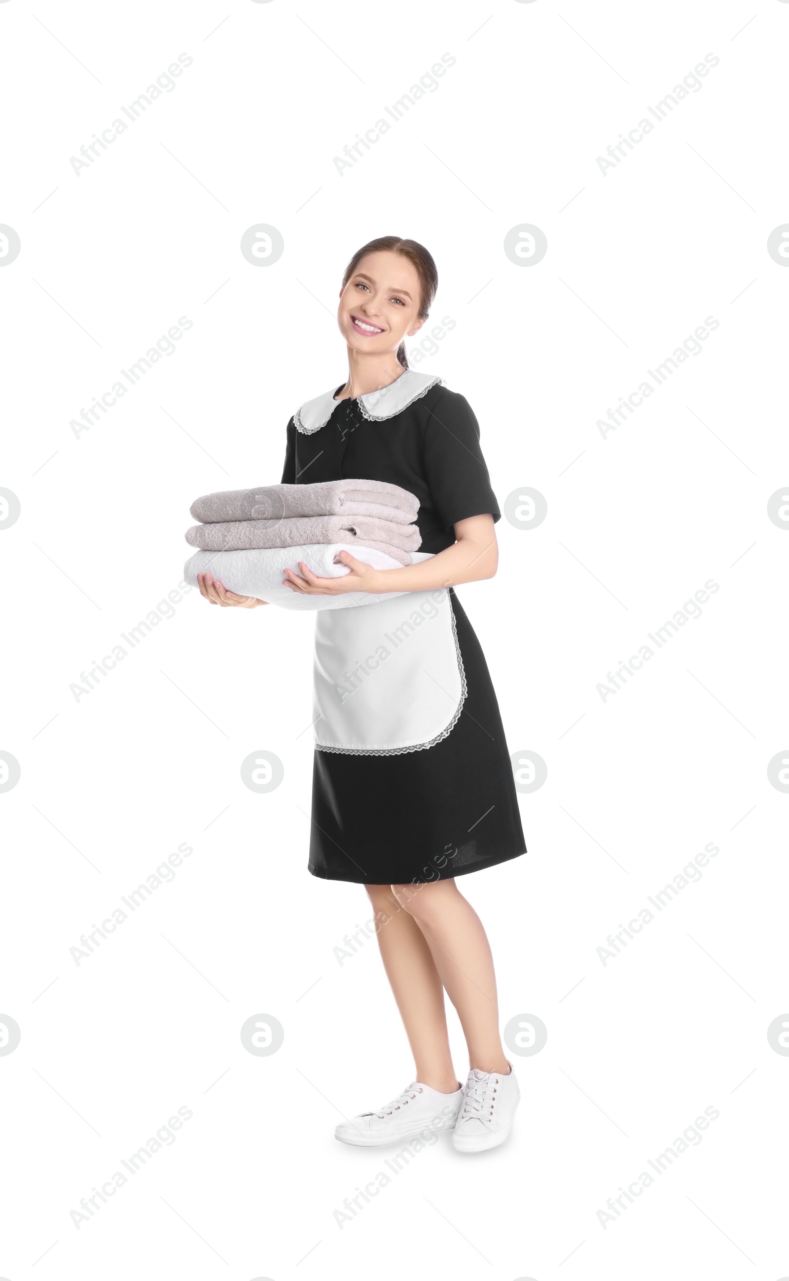 Photo of Young chambermaid holding stack of fresh towels on white background