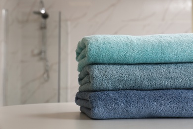 Photo of Stack of clean towels on table in bathroom, closeup. Space for text