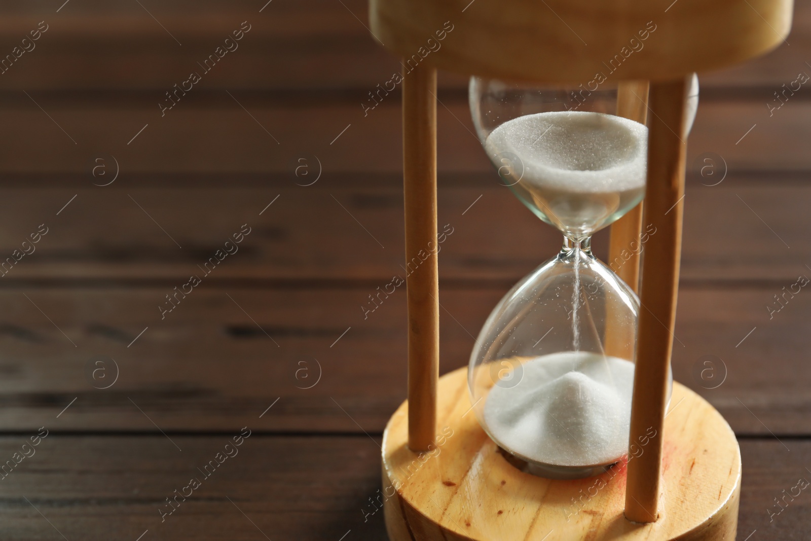 Photo of Hourglass with flowing sand on table. Time management