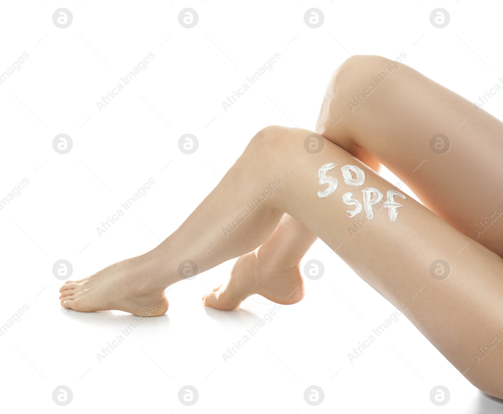 Photo of Text 50 SPF written with sun protection cream on woman's leg against white background, closeup