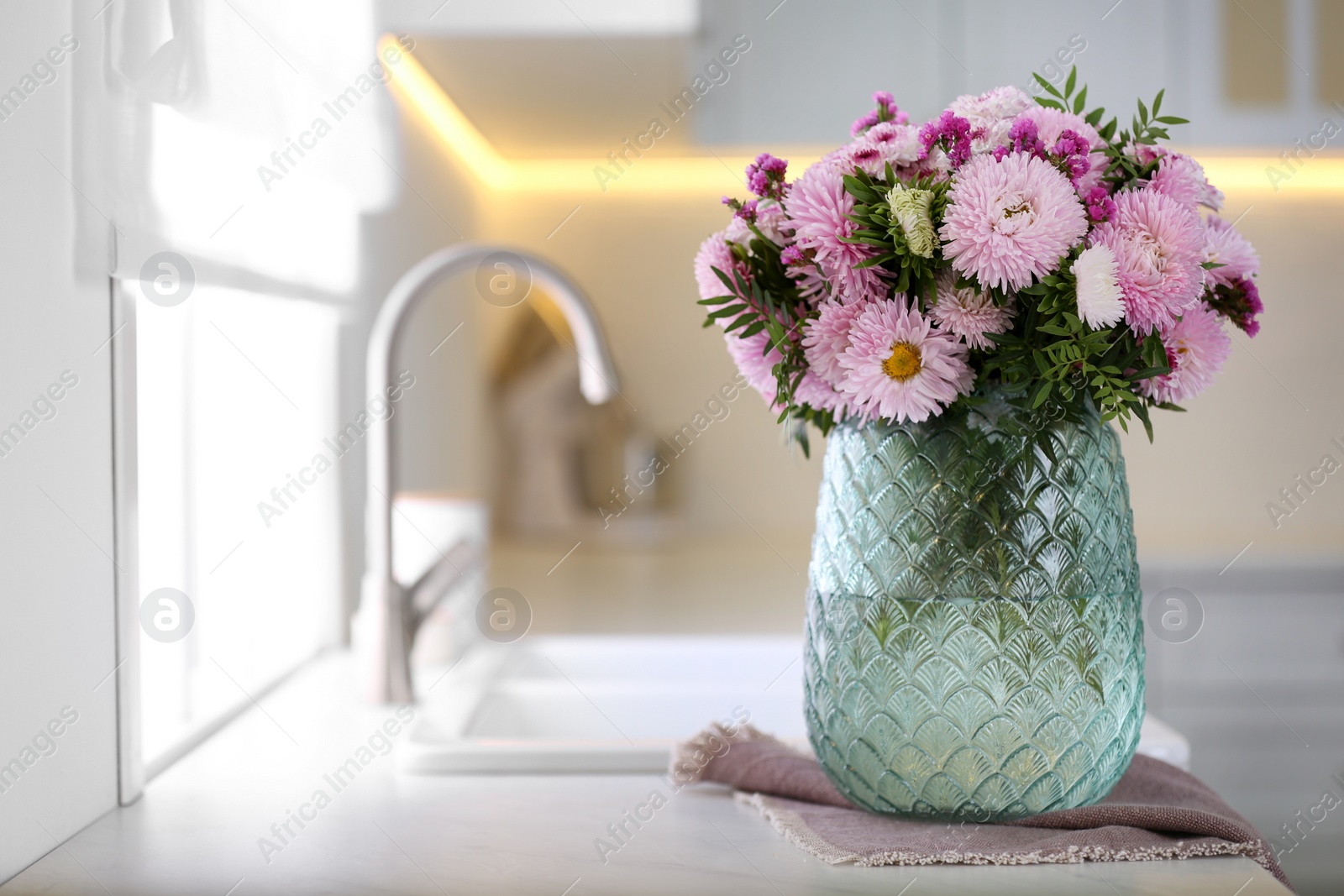 Photo of Vase with beautiful chrysanthemum flowers on countertop in kitchen, space for text. Interior design