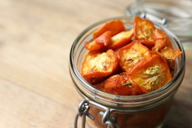 Glass jar with cut dried kumquat fruits on wooden table, closeup