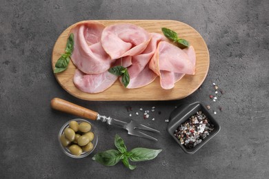 Photo of Tasty ham with basil, olives and spices served on grey table, flat lay