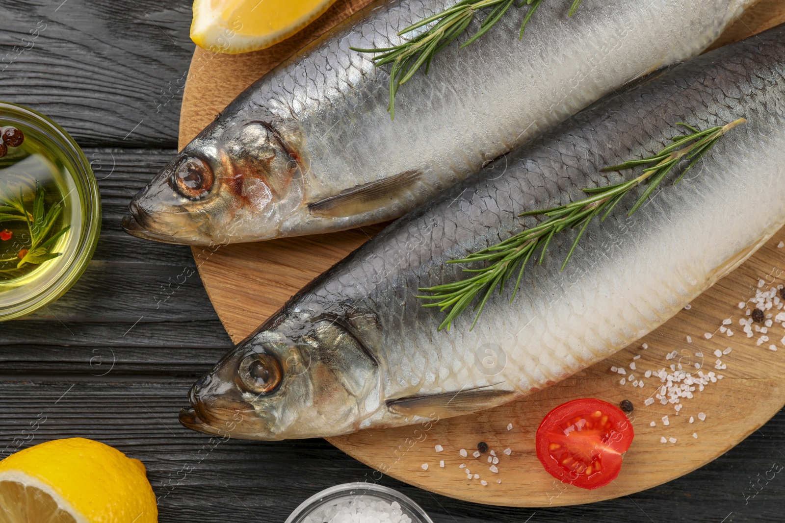 Photo of Delicious salted herrings and ingredients on black wooden table, flat lay