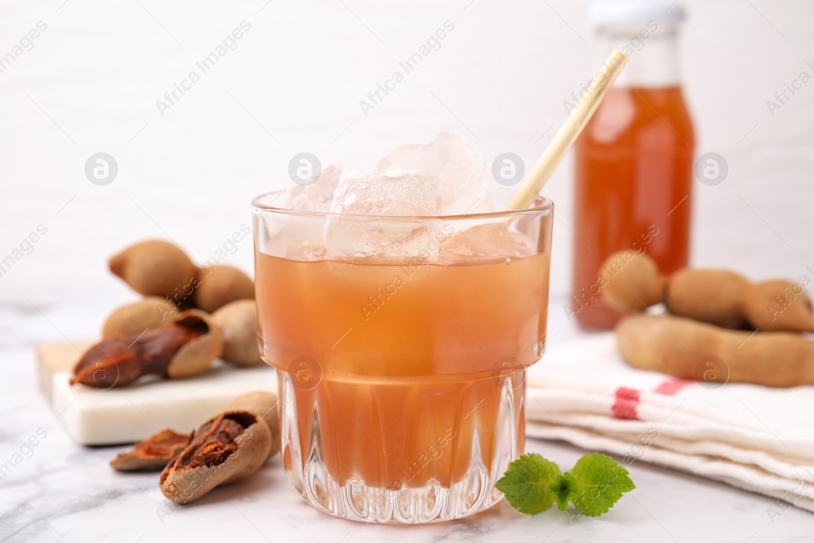 Photo of Freshly made tamarind juice with mint on white marble table, closeup