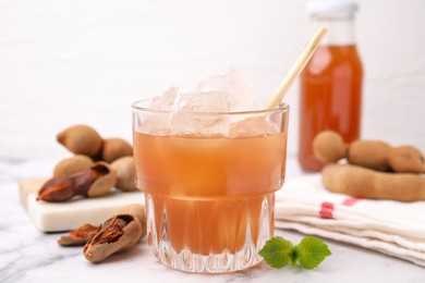 Photo of Freshly made tamarind juice with mint on white marble table, closeup