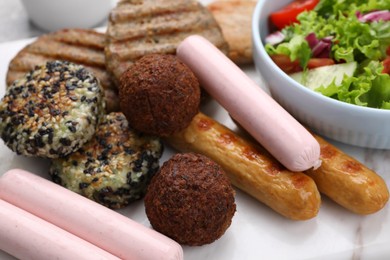 Different tasty vegan meat products and fresh vegetable salad on white marble table, closeup