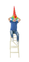 Photo of Little boy in clown costume on stool against white background. April fool's day