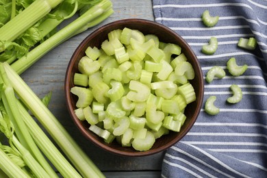Fresh cut celery stalks in bowl and bunches on wooden table, flat lay