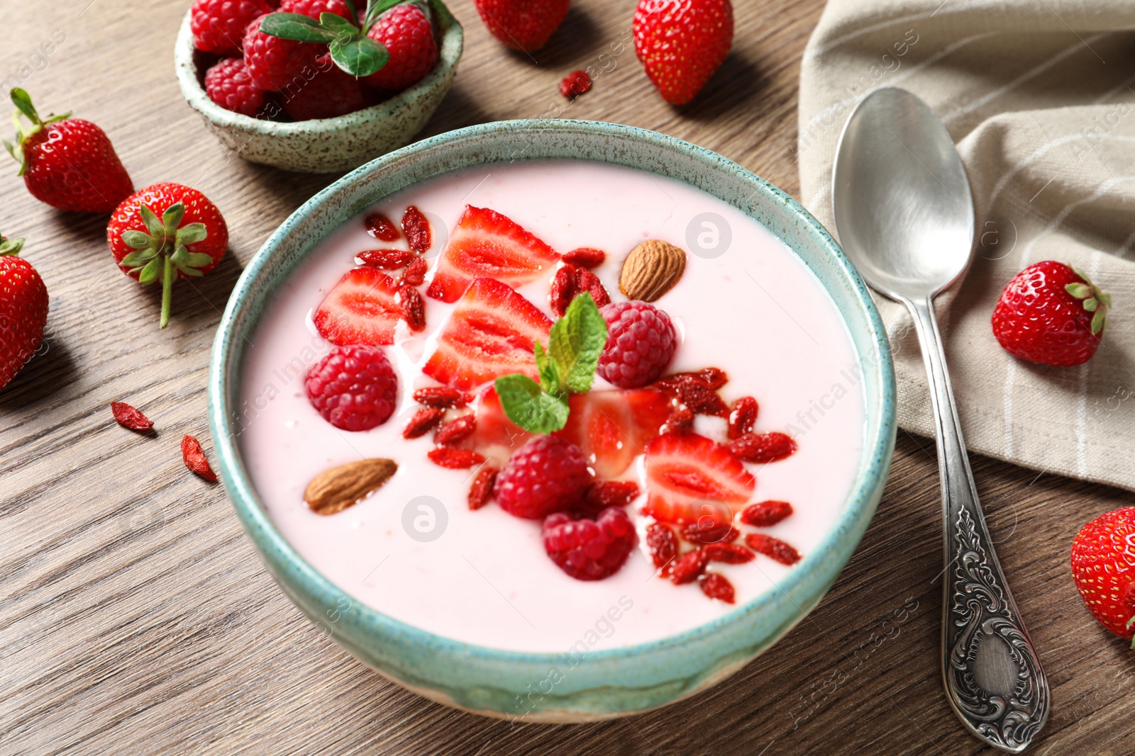 Photo of Smoothie bowl with goji berries and spoon on wooden table