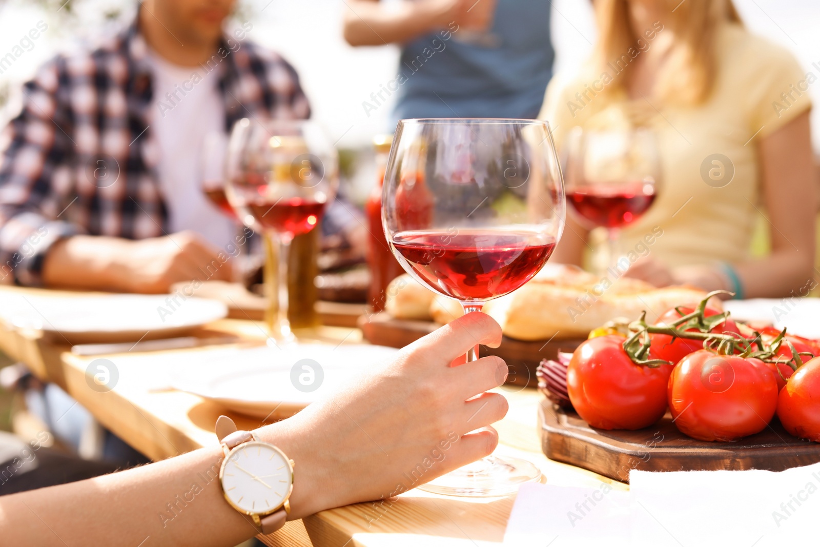 Photo of Young people with glasses of wine at table outdoors. Summer barbecue