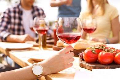 Young people with glasses of wine at table outdoors. Summer barbecue