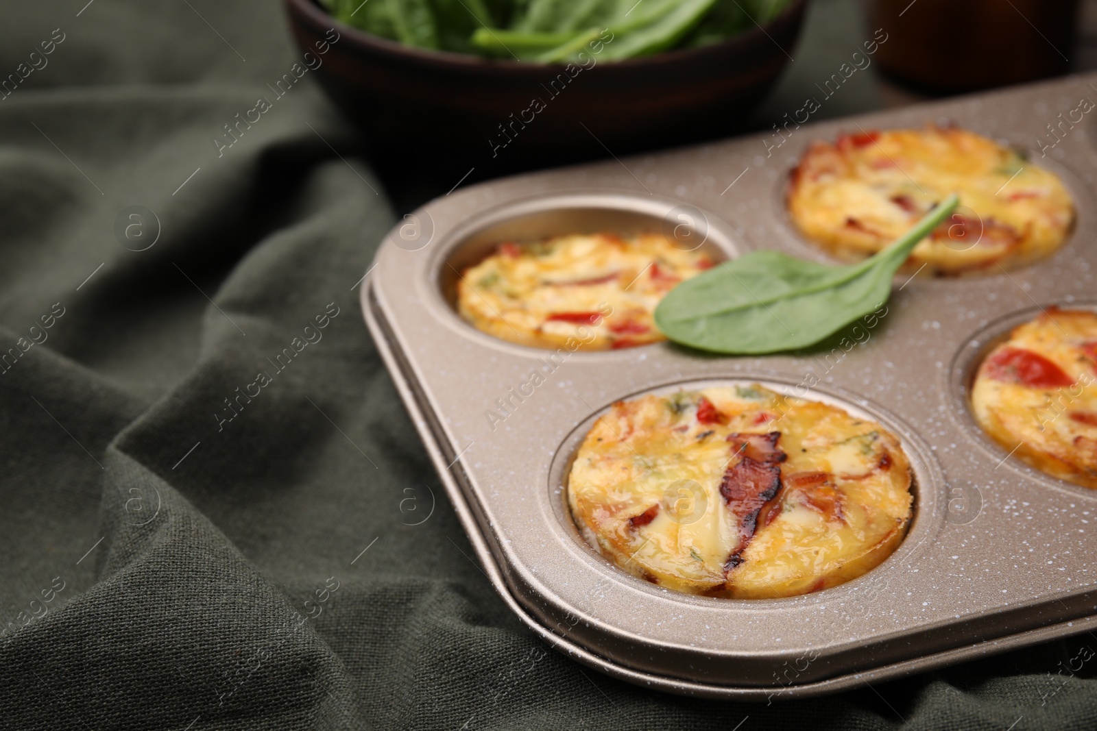 Photo of Freshly baked bacon and egg muffins with cheese in tin on table, closeup. Space for text