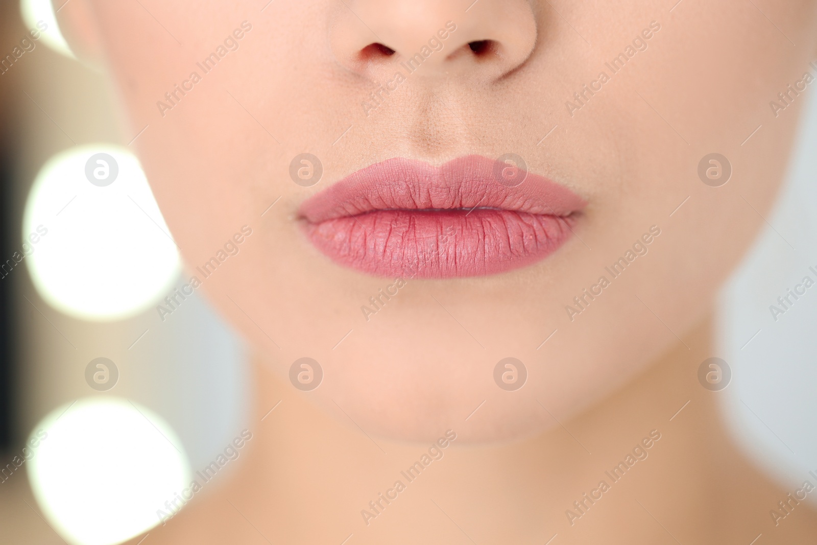 Photo of Young woman wearing beautiful lipstick on blurred background, closeup
