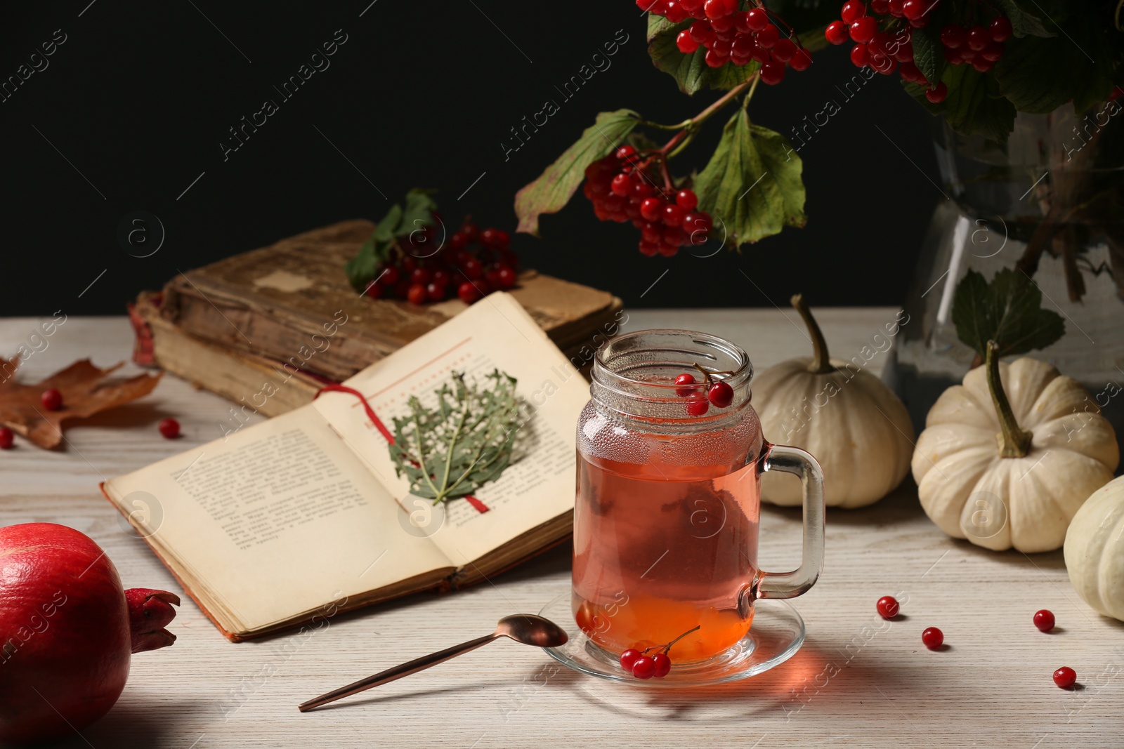 Photo of Delicious viburnum tea, books and pumpkins on wooden table. Cozy autumn atmosphere