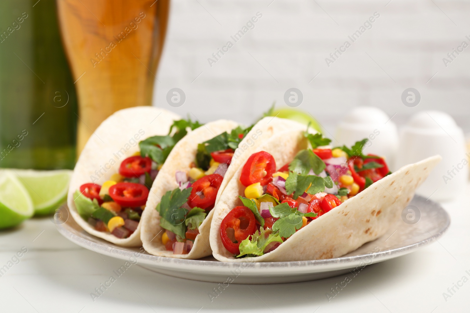 Photo of Tasty tacos with vegetables on white marble table, closeup