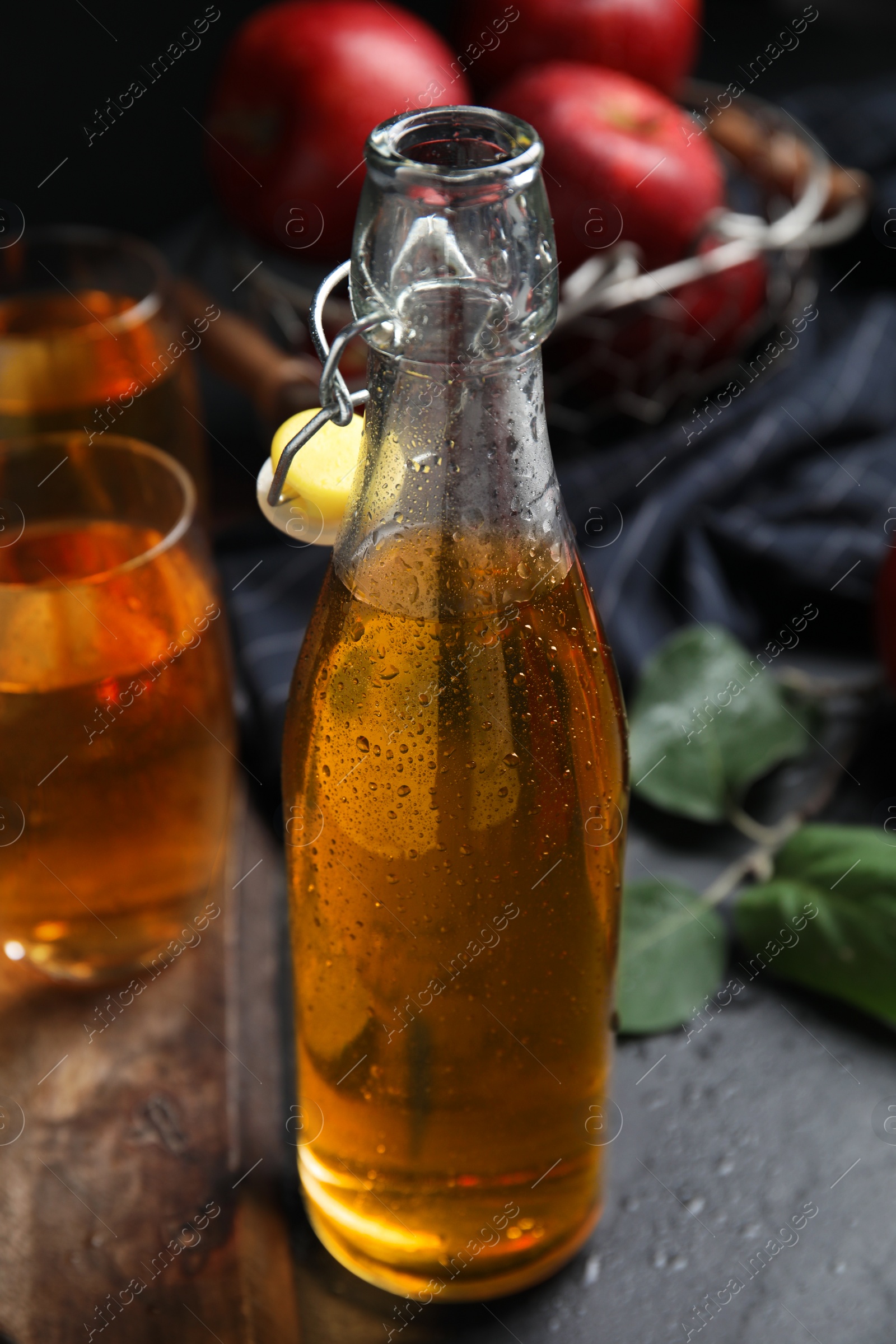 Photo of Delicious apple cider in glass bottle on black table