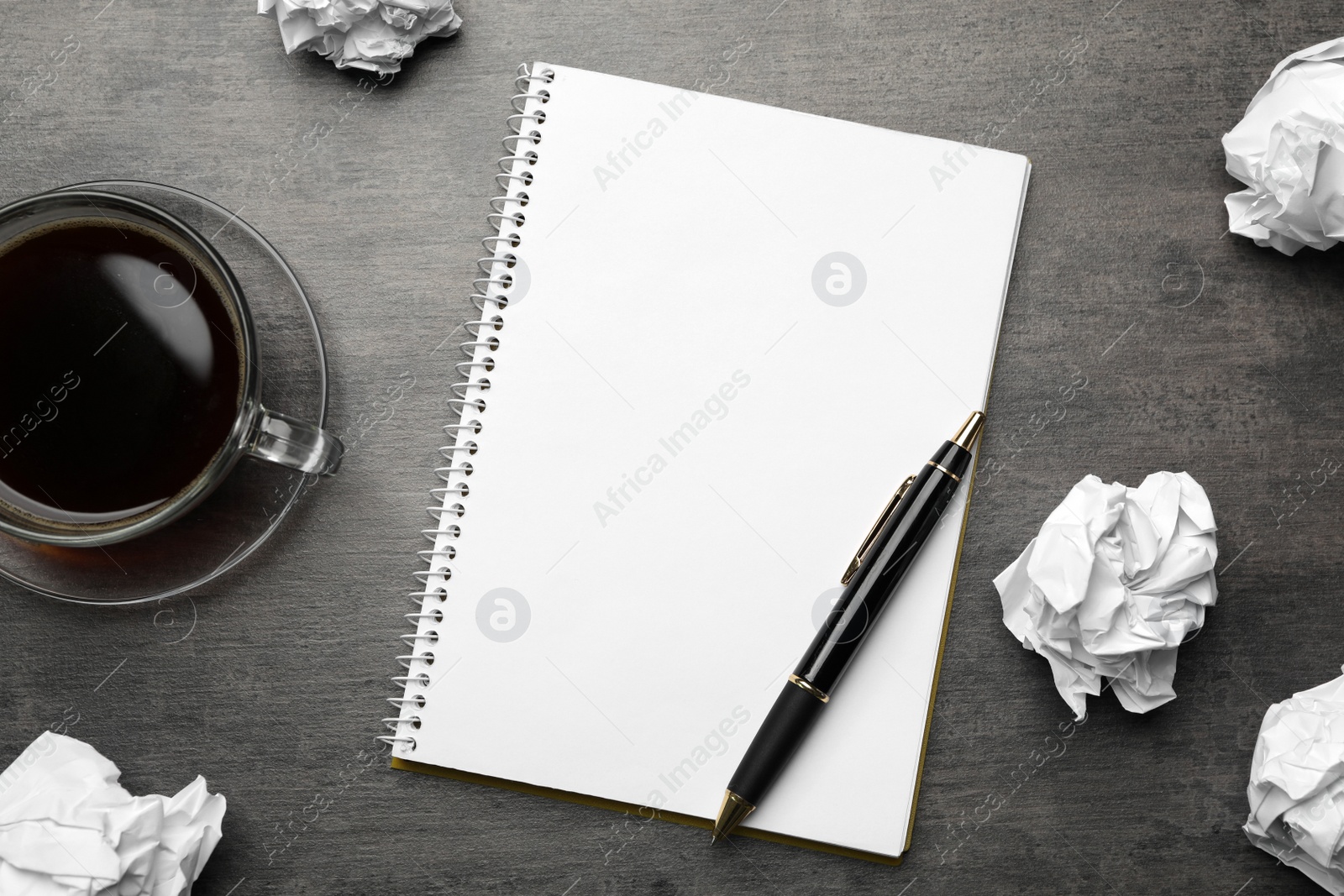 Photo of Flat lay composition with crumpled paper balls and empty notebook on grey table. Space for text