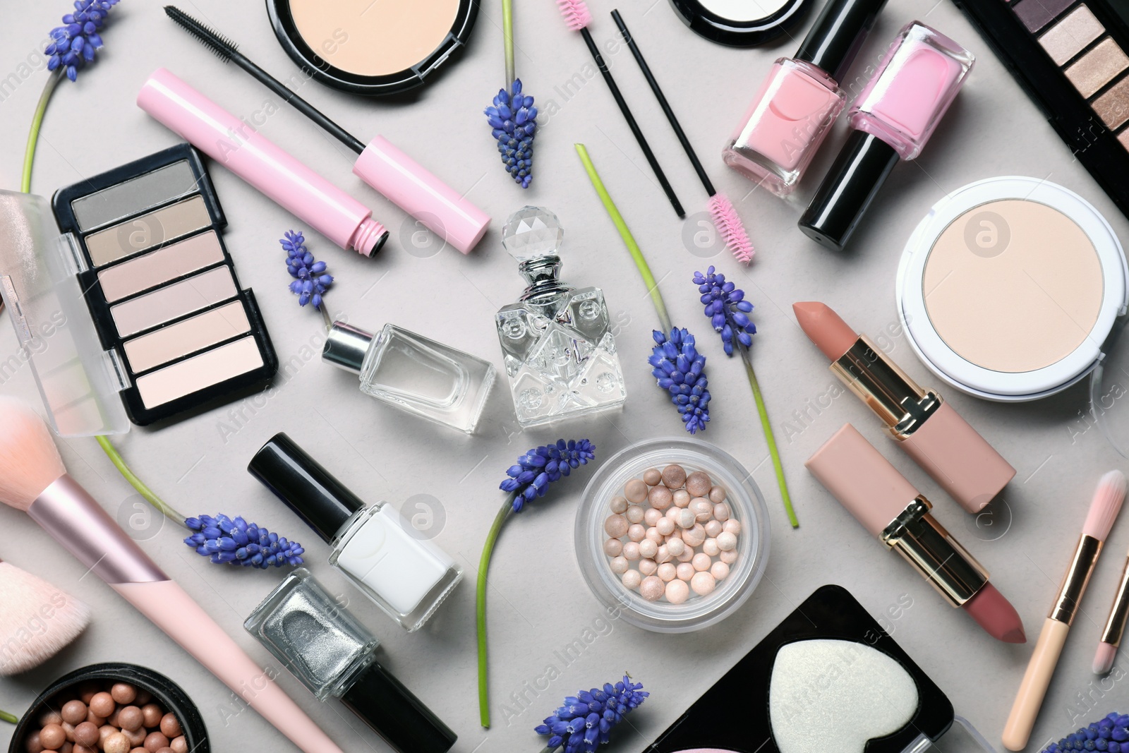 Photo of Flat lay composition with different makeup products and beautiful spring flowers on gray background