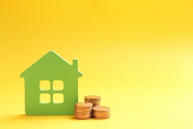 House figure and coins on color background. Space for text