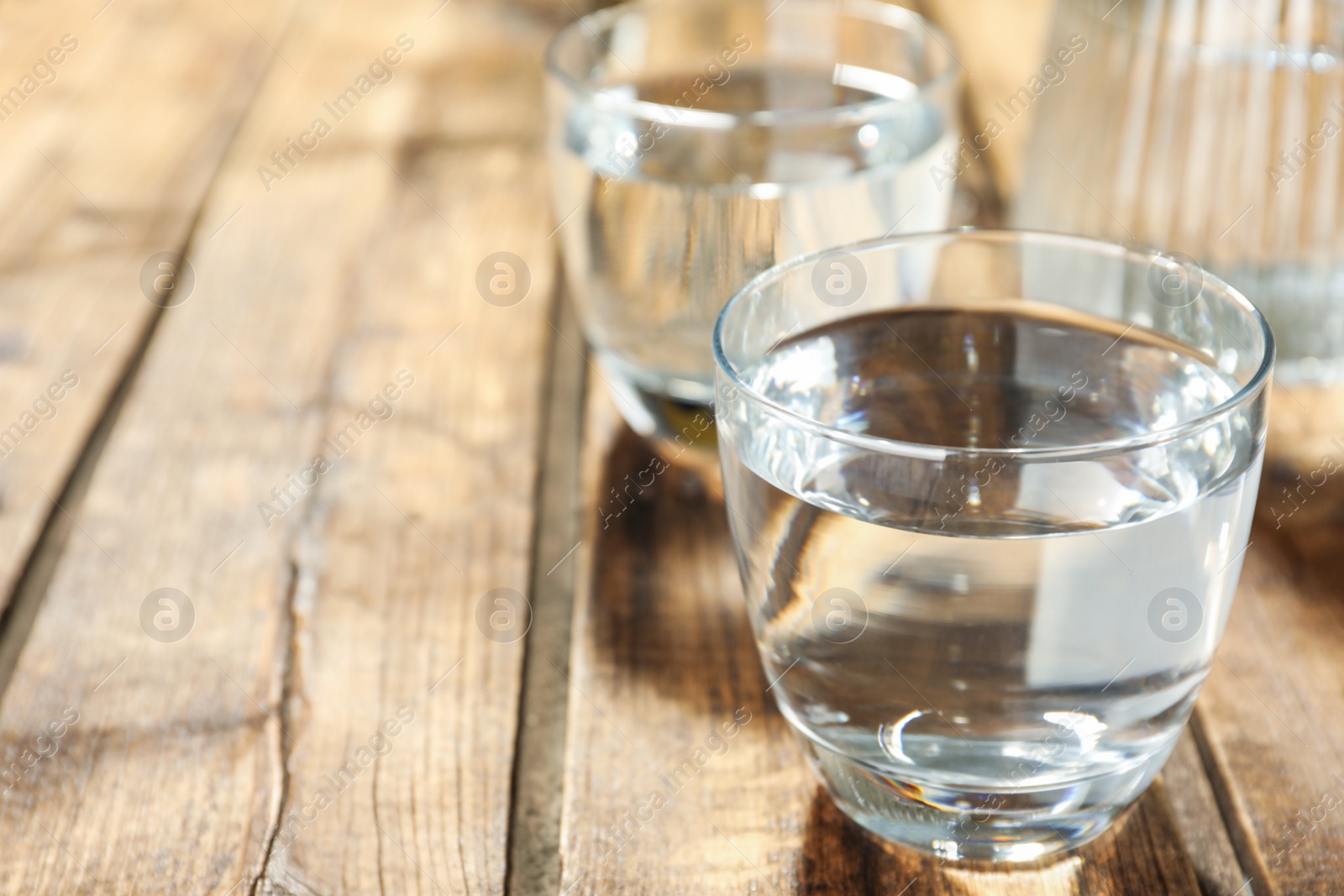 Photo of Glass of water on wooden table, closeup with space for text. Refreshing drink