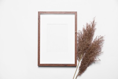 Empty photo frame and dry decorative spikes on white background, top view. Space for design