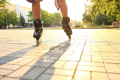 Photo of Young man roller skating outdoors on sunny day, closeup. Recreational activity