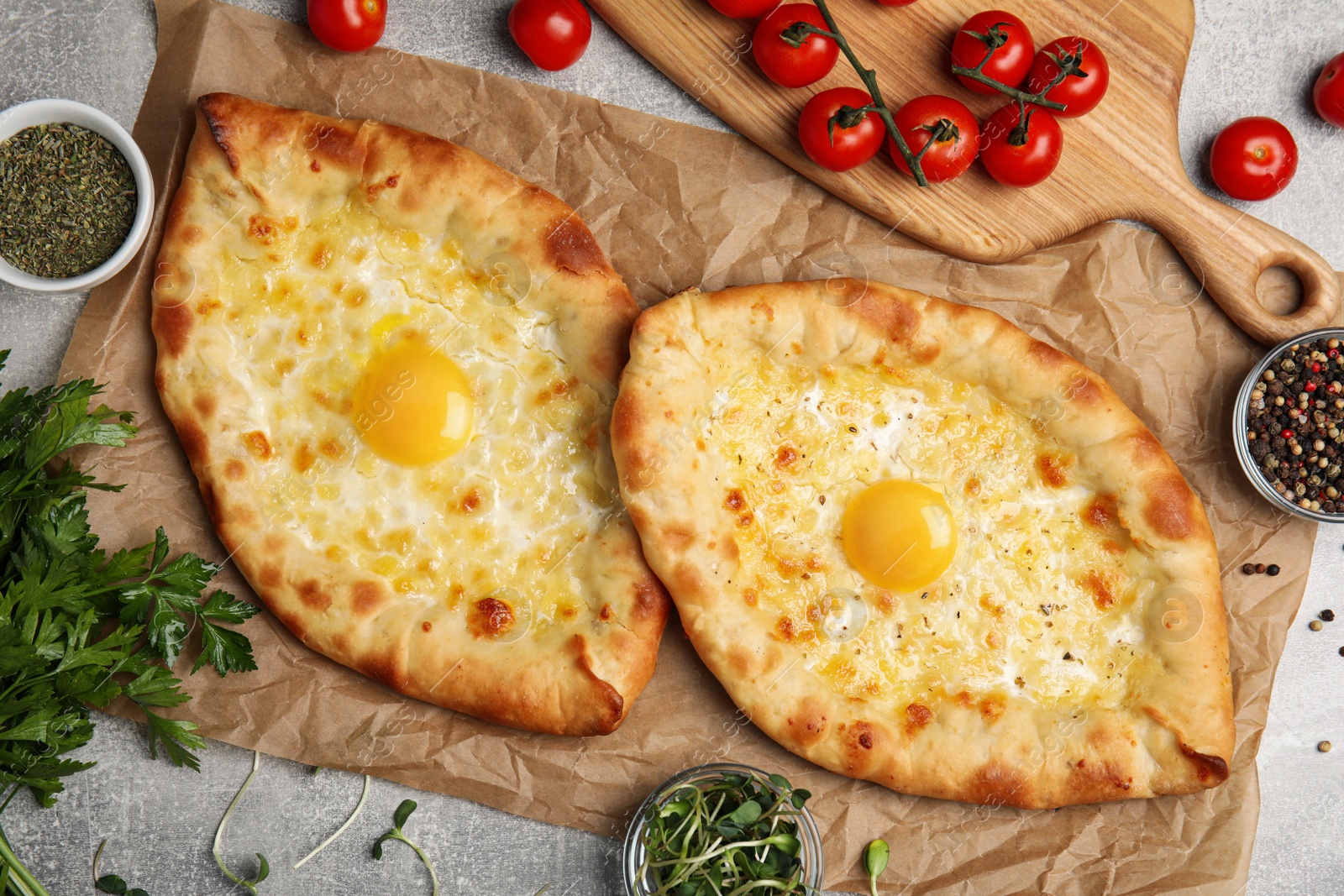 Photo of Fresh delicious Adjarian khachapuris served on grey table, flat lay