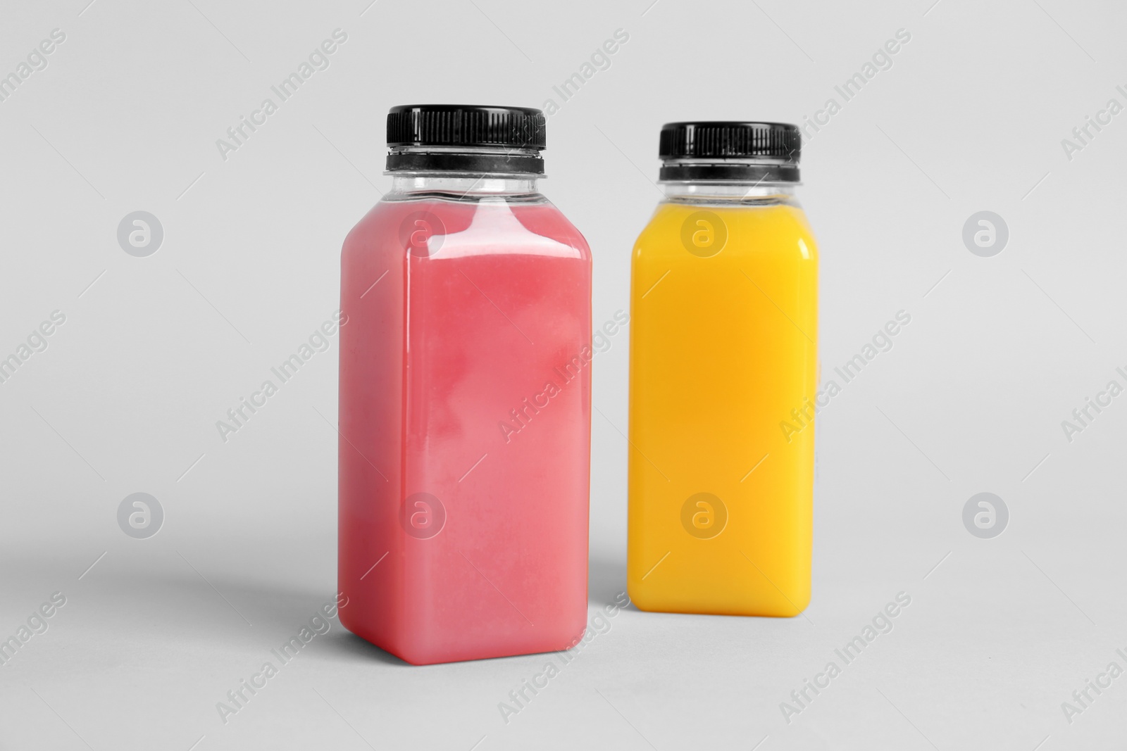 Photo of Bottles with delicious colorful juices on light background