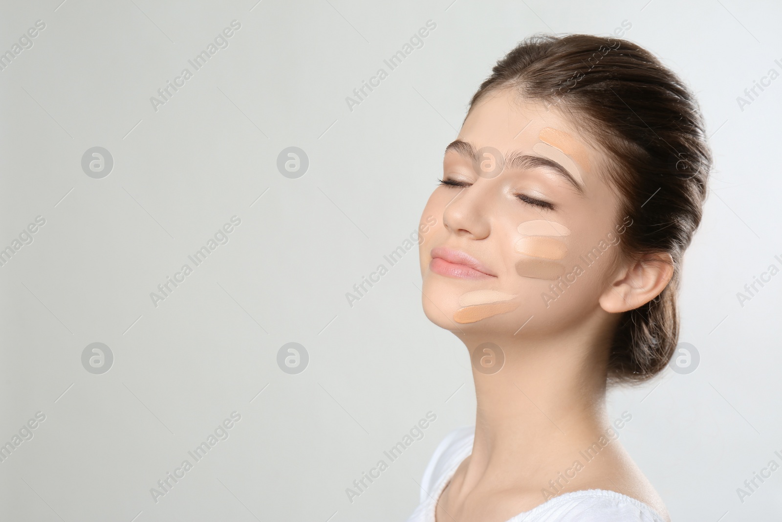 Photo of Beautiful girl on light grey background. Using concealers and foundation for face contouring