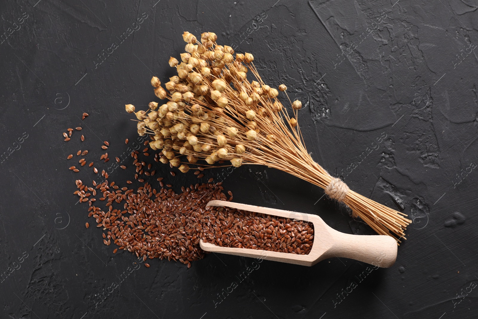 Photo of Flax seeds and dry flowers on grey textured table, flat lay