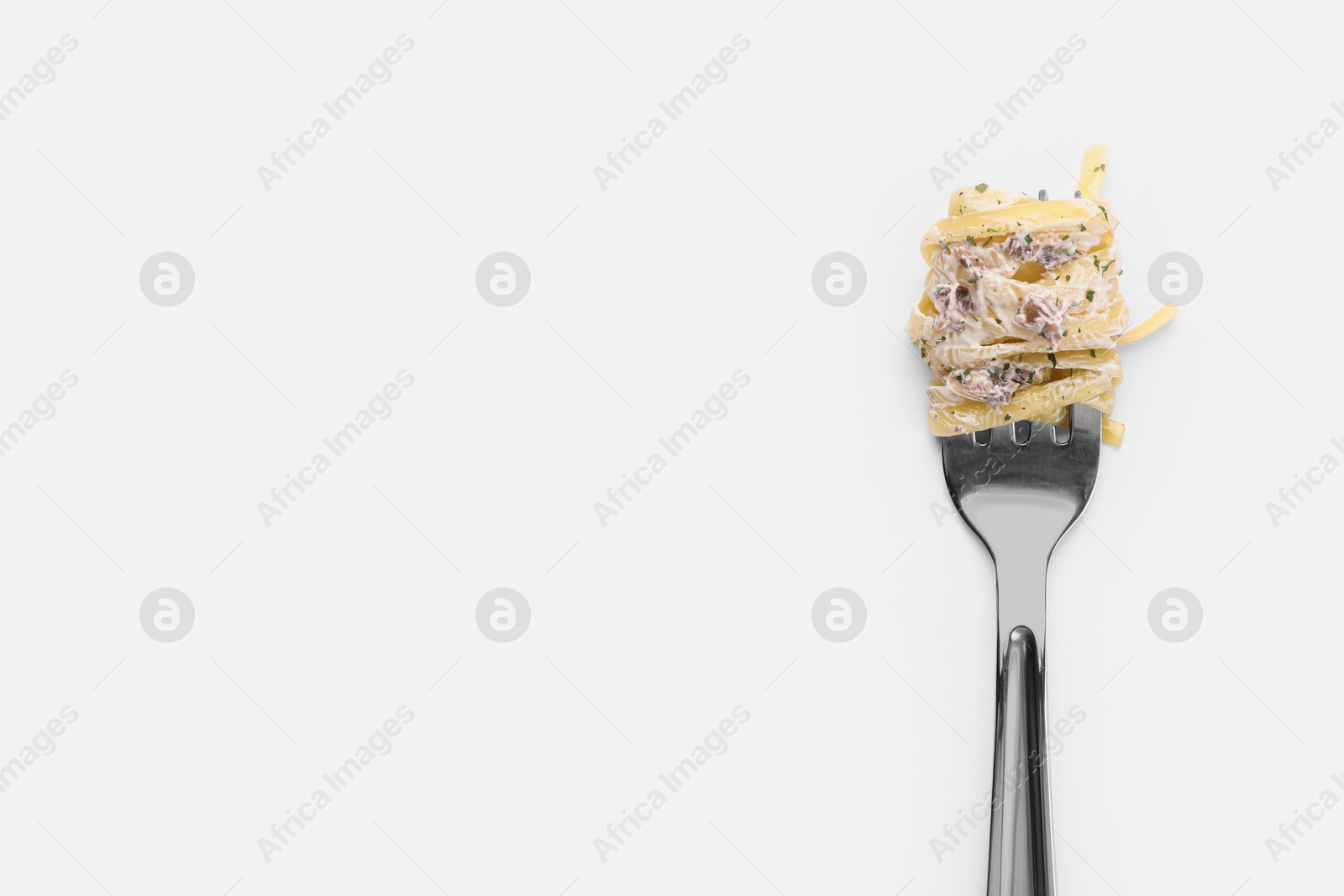 Photo of Fork with tasty pasta on white background, top view. Space for text