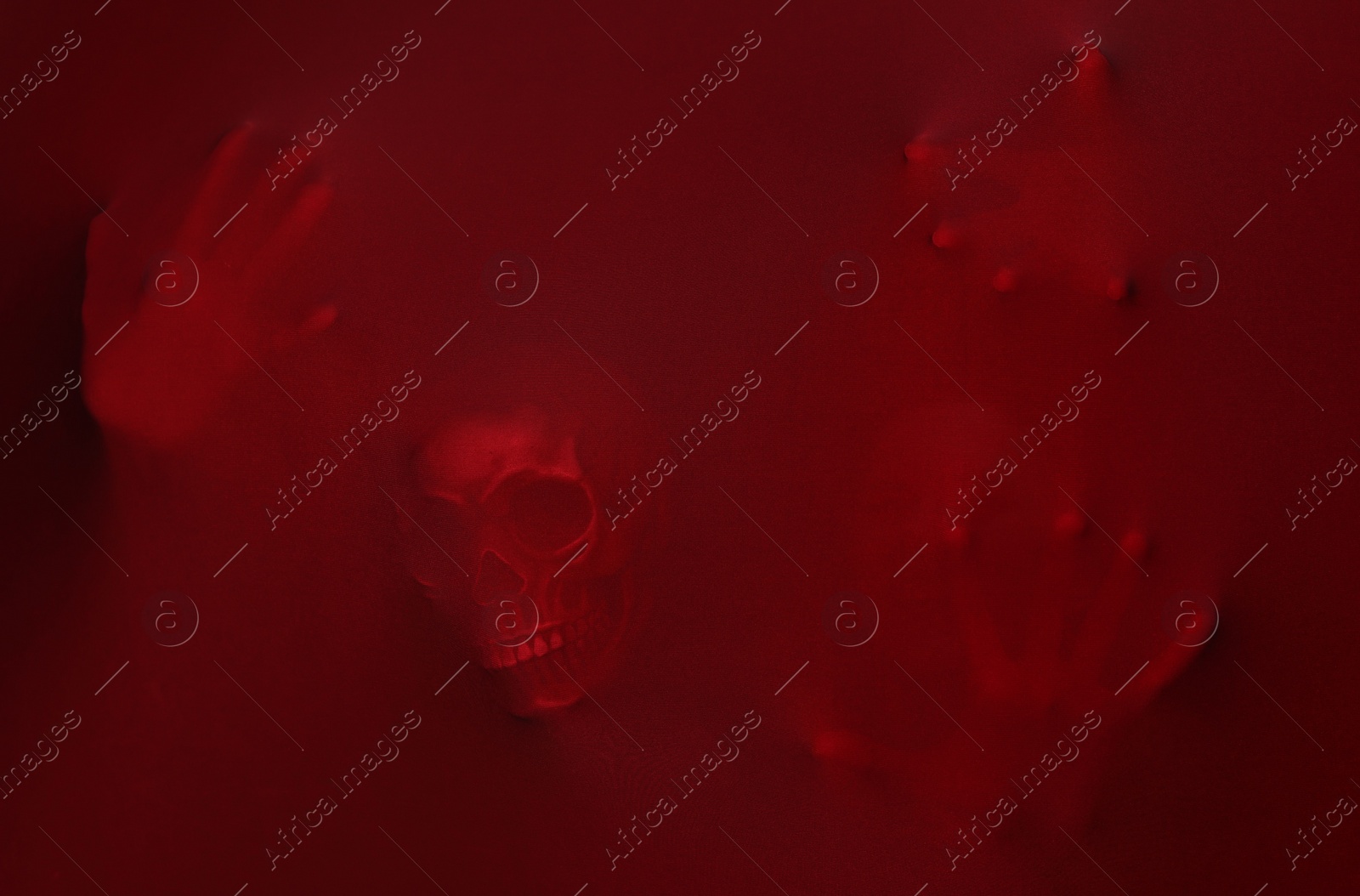 Photo of Silhouette of creepy ghost with skull behind red cloth