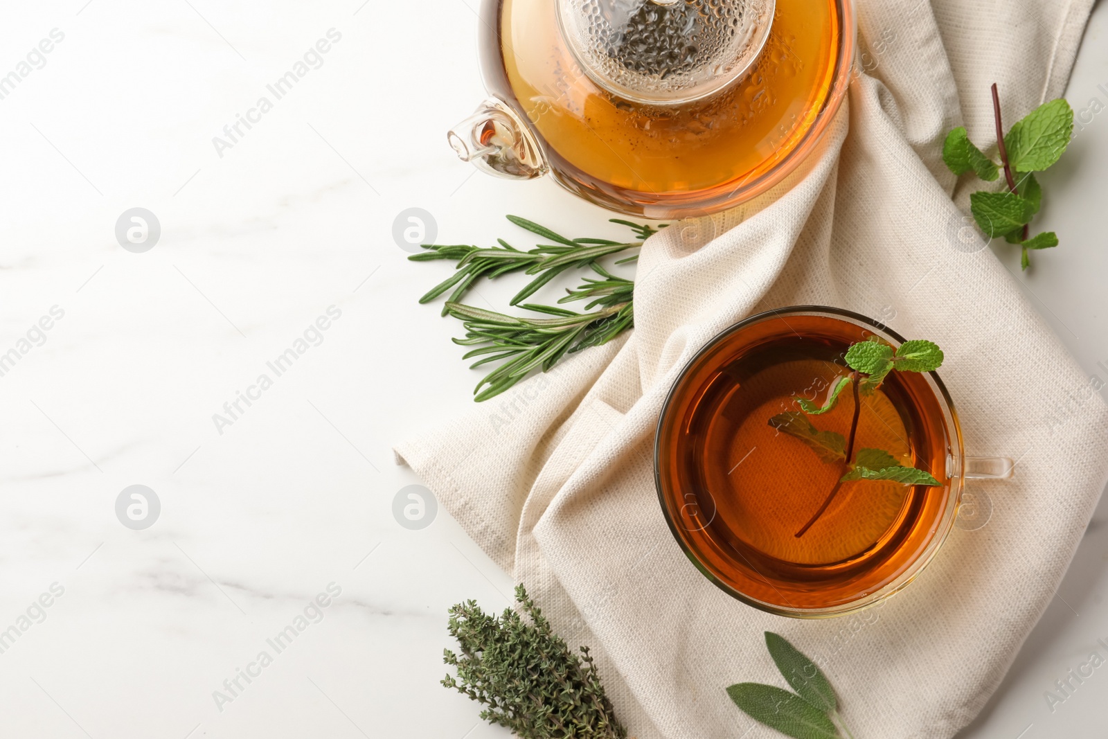Photo of Aromatic herbal tea with rosemary, sage, thyme and mint on white marble table, flat lay. Space for text