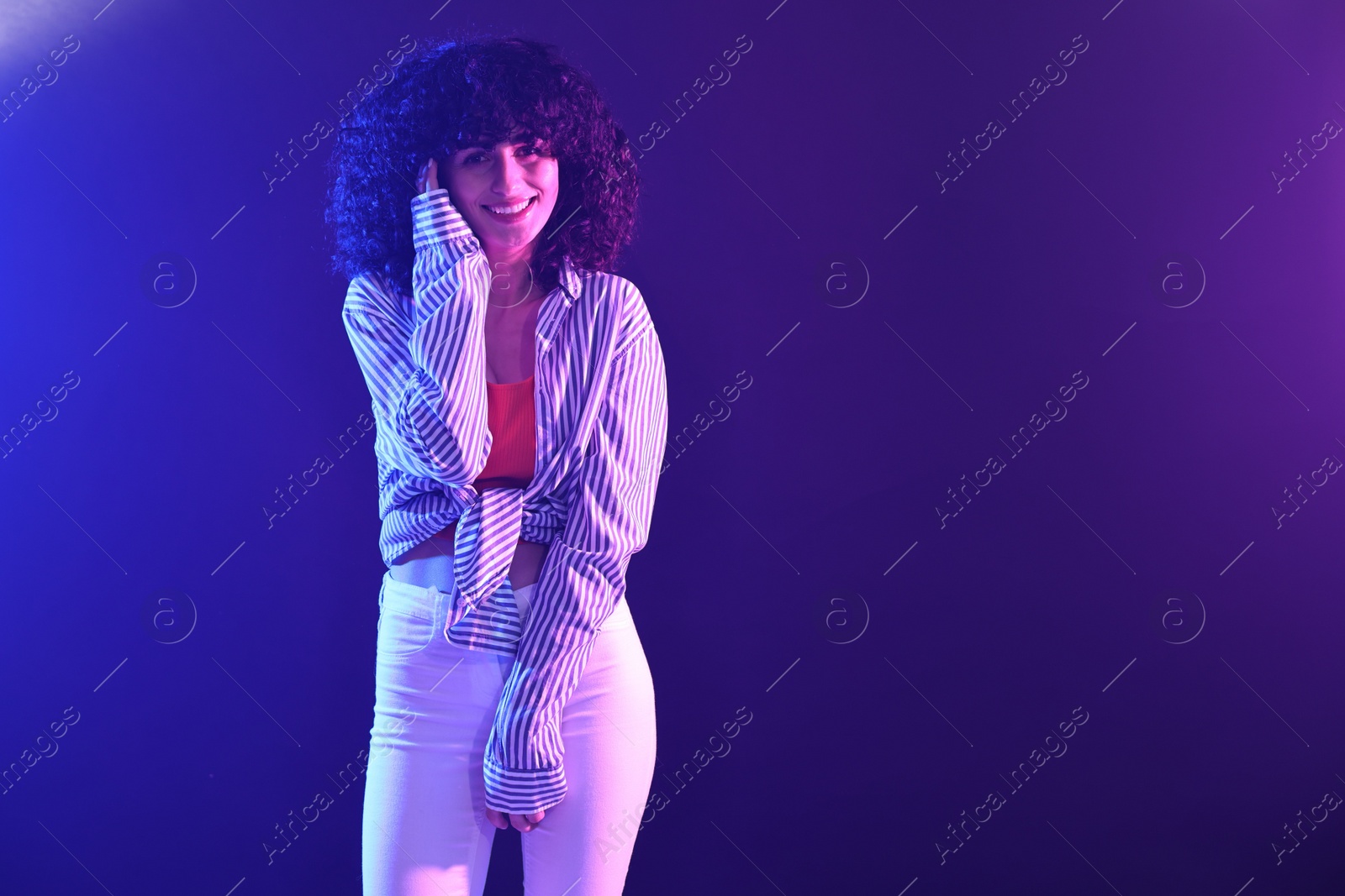 Photo of Beautiful young woman posing on color background in neon lights. Space for text