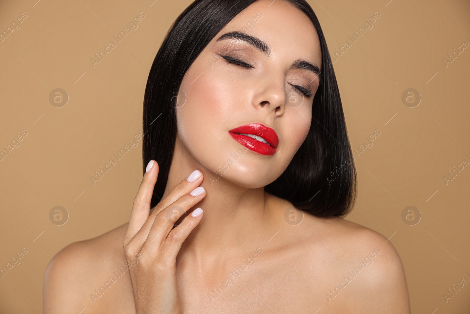 Photo of Portrait of young woman wearing beautiful red lipstick on beige background